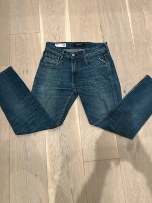 Blå jeans från Replay - Snygga blå jeans från Replay med klassisk femficksdesign och diskreta slitningar. Jeansen har raka ben och normal midja. Tillverkade i denim med en lätt stretch för extra komfort. Perfekta för en avslappnad och trendig look.