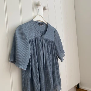 Blå blus med mönster - En fin blå blus från UK med knytning och två knappar framtill. Tyget är veckat och mönstrat. Storlek S🩷. Inga tecken på användning. 