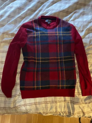 Röd rutig stickad tröja Club Room - Stickad tröja från Club Room i rött med rutigt mönster i marinblått, gult och svart på framsidan. Långa ärmar, rund halsringning och enfärgad baksida. Klassisk design, säljer pga inte min stil.