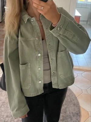 Grön jeansjacka - Snygg ljusgrön jeansjacka med stora framfickor och silverfärgade knappar. Jackan har klassisk krage och raka ärmar. Perfekt för en avslappnad och trendig look.