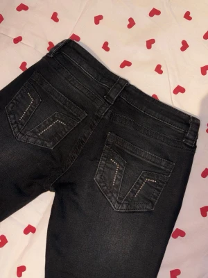Svarta jeans från Gina Tricot - Säljer ett par svarta low Waits bootcut jeans i nyskick som aldrig är använda från Gina Tricot med snygga detaljer i form av nitar på bakfickorna. Innebenslängd: 82 cm 