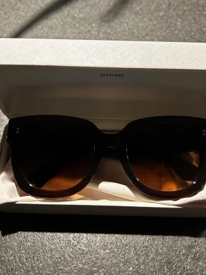 Bruna solglasögon från CHIMI - Snygga solglasögon från CHIMI med brun, rundad båge och mörka glas. Perfekt accessoar för att höja din stil under soliga dagar. Knappt använda därav säljer jag de 💕