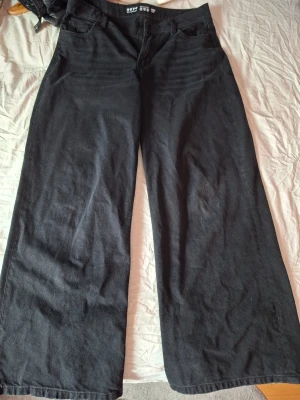Svarta wide leg jeans från primark london - Säljer ett par svarta wide leg jeans från H&M med hög midja och fem klassiska fickor. Jeansen har en avslappnad passform och är tillverkade i ett mjukt denimtyg. Perfekta för dig som gillar en trendig och bekväm stil.
