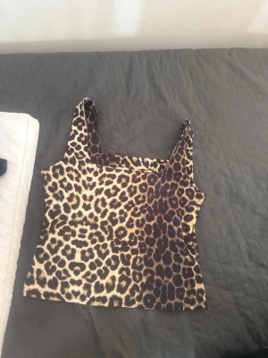 Leopardmönstrad linne-topp - Säljer en snygg leopardmönstrad linne-topp med breda axelband. Toppen har en croppad passform och är perfekt för dig som vill sticka ut. Materialet känns mjukt och stretchigt, troligen polyester eller bomullsmix. Perfekt att matcha med jeans eller kjol.