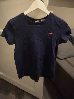 Mörkblå Levi's t-shirt i bomull - Säljer en mörkblå t-shirt från Levi's i mjuk bomull. Klassisk passform med korta ärmar och rund halsringning. Diskret Levi's-logga på bröstet. Perfekt till jeans eller shorts för en enkel och clean look. den är i storlek XXS men passar mig bra som oftast är en xs / s 
