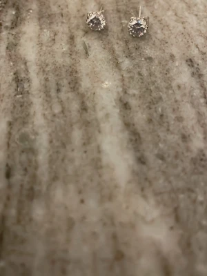 Silvriga örhängen med klar sten, Riktigt silver men inte riktig diamant! - Säljer ett par stilrena silver örhängen med rund, klar sten i mitten. Klassisk design med stift och fjärilslås, perfekta för dig som gillar minimalistiska. Det är riktigt silver  och stenen ger ett snyggt bling. passar när som helst och i vardagen! Bara andlöst en gång. OBS! har gjort rent och doppat i slivedipp ifall silvret försvinnern eller rostar.