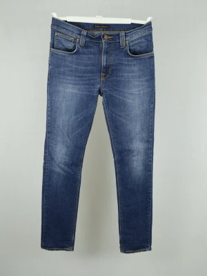 Nudie Jeans  - NUDIE JEANS Storlek : 31/32 Modell : Thin Finn Mått : A = 40CM - B = 107CM Användning : Jeansen är i ett fint skick utan defekter Nypris : Cirka 2000SEK Modellen på bilden : 182CM och väger 78KG
