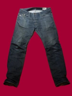 Diesel Darron jeans blå tapered 32/32 - (PRIS GÅR ATT DISKUTERA)Säljer ett par blå Diesel Darron jeans i regular slim-tapered modell. Klassisk femficksdesign, snygga slitningar och detaljerade sömmar på bakfickorna. Jeansen är i ett mjukt denimtyg och har en något smalare passform nedtill.