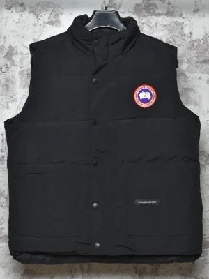 Svart dunväst med logga - Snygg svart dunväst med hög krage och tryckknappar framtill. Västen har det klassiska runda märket på bröstet och två stora fickor framtill. Perfekt för lager-på-lager och riktigt varm känsla.