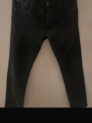 Nudie Jeans grim Tim - Säljer ett par svarta jeans från Nudie Jeans med klassisk femficksmodell och knappgylf. Jeansen har en smal passform och är tillverkade i slitstark denim. Perfekta för dig som gillar en clean och tidlös look. W33 L32 modell Grim Tim