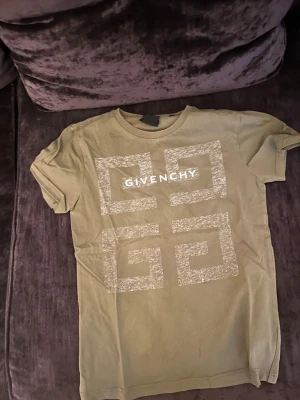 Grön Givenchy t-shirt med tryck - Snygg grön t-shirt från Givenchy med stort vitt grafiskt tryck och logga på bröstet samt liten logga i nacken. Klassisk rund hals och korta ärmar. Perfekt för dig som gillar streetwear och exklusiva märken.