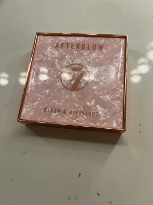 W7 Afterglow Blush & Highlight - Säljer en W7 Afterglow Blush & Highlight-palett i en lyxig roséguldig förpackning. Innehåller flera nyanser i skimrande rosa, beige och lila toner som ger både färg och glow till kinderna. Perfekt för att skapa en fräsch och strålande look.
