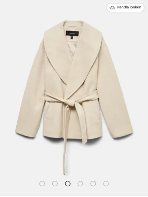 Beige kappa med knytskärp - Stilren beige kappa från vero Moda med bred sjalkrage och knytskärp i midjan. Kappan har två fickor framtill och är tillverkad i ett mjukt, ull-liknande material. Perfekt för dig som vill ha en enkel men trendig look.