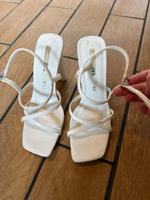 Vita klackar / klackskor Zara - Vita klackar från Zara i storlek 39 med hög klack och band man stänger runt ankeln. Sparsamt använda med har fått en färg fläck på klacken (se sista bild). Använda typ 1-2 gånger.