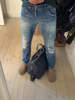 Dondup jeans - Säljer ett par mycket fräscha blå jeans från Dondup med snygga slitningar på knäna. Jeansen har normal midja och raka ben altså inte för tajta. Perfekta för en avslappnad stil till sommaren.