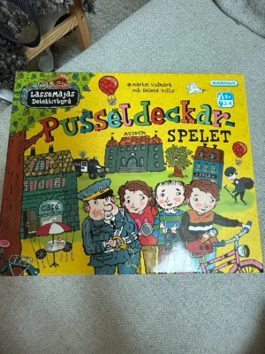 LasseMajas Pusseldeckarspel - Roligt brädspel från LasseMajas Detektivbyrå, Pusseldeckar-spelet. Spelet har färgglad design med illustrationer av karaktärer och miljöer från böckerna. Innehåller spelplan, kort, pjäser och tärning. Perfekt för dig som gillar mysterier och pussel.oannvänt.