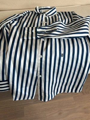 Randig skjorta från Stenströms - Snygg skjorta från Stenströms med breda marinblå och vita ränder. Klassisk krage, knäppning framtill och lång ärm. Skjortan har en broderad logga på bröstet och är tillverkad i bomull för en skön känsla.