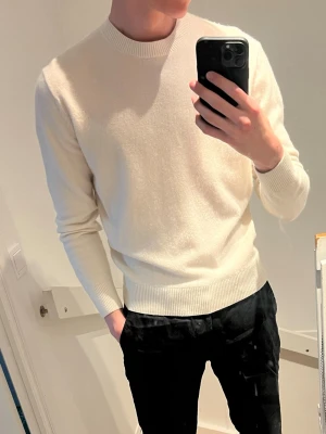 Vit stickad tröja Massimo Dutti - Säljer en stilren vit stickad tröja från Massimo Dutti. Tröjan har rund halsringning, ribbade muddar och är tillverkad i mjukt material som ger en clean look. Perfekt till svarta byxor eller jeans. Noppig men annars i bra skick!