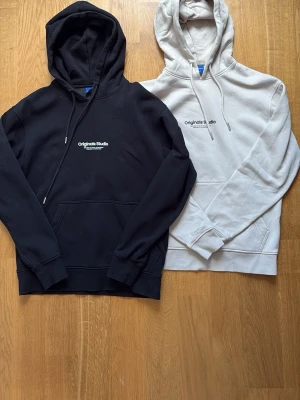 Svart och vit hoodie Originals Studio - Två hoodies från Originals Studio, en svart och en vit. Passar perfekt till det mesta. Håller varmen och är väldigt bekväma. Strl S. 2-pack. Jag har knappt använt dom och de är i väldigt fint skick. Skriv om du undrar något. Pris kan även diskuteras👍