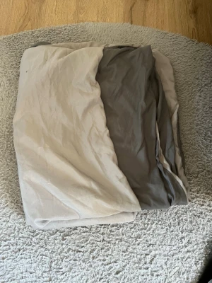 Sängkläder - Säljer ett stilrent påslakan i bomull med tvåfärgad design, ena sidan beige och andra sidan grå. Perfekt för dig som vill ha en enkel men snygg look i sovrummet. Mjukt material och passar de flesta täcken. Dragkedjan har gått sönder på påsklakanet därav priset. Passar till 150x210 cm