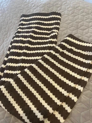 Brunvita randiga leggings från MISU - Säljer ett par snygga leggings från MISU i storlek L. De är brunvita med vågiga ränder och har en mjuk, stickad känsla. Perfekta för dig som gillar retrovibbar och vill ha något bekvämt men ändå trendigt. Elastisk midja för skön passform.