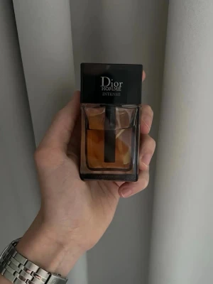 Dior Homme Intense  - Runt 40 av 50ml kvar. Dior Homme Intense är en lyxig herrparfym med elegant designad glasflaska och svart lock. Doften är varm och sofistikerad, perfekt för dig som gillar exklusiva parfymer. Flaskan har en stilren, fyrkantig form och innehållet är bärnstensfärgat.