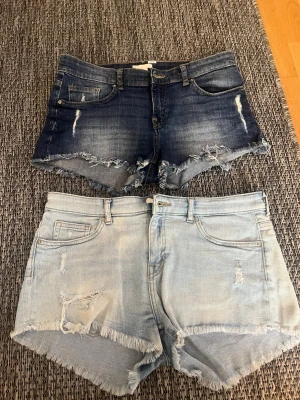 Två par jeansshorts med fransig kant - Säljer två par jeansshorts, ett par i mörkblå denim och ett par i ljusblå denim. Båda har fransig kant nertill och slitna detaljer framtill. Klassisk femficksmodell med knapp och dragkedja. Perfekta för sommaren! Båda i  storlek 38 från HM. Skriv om ni bara vill ha ett av paren