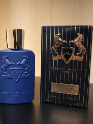 Parfums de Marly Layton - 125ml - Lyxig parfym från Parfums de Marly, Layton Royal Essence. Flaskan är mattblå med silverfärgad kork och har ett upphöjt emblem med två hästar och siffran 1743. Kommer i elegant blå ask med gulddetaljer. Volym: 125 ml.