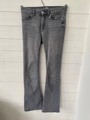 Grå bootcut jeans med fem fickor - Snygga grå jeans i bootcut-modell med normal midja. Jeansen har en lätt tvättad look och stängs med dragkedja och knapp. Perfekta för en avslappnad och trendig stil. Lite slitna på backfickan vilket ger en retro look.