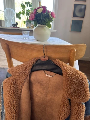 Brun teddyjacka från Giovanni - Säljer en snygg teddyjacka från Giovanni i brun färg med fluffigt foder och krage. Jackan har en klassisk teddylook och är perfekt för att hålla värmen under kyliga dagar. Materialet är mjukt och mysigt, vilket ger en trendig och avslappnad stil.