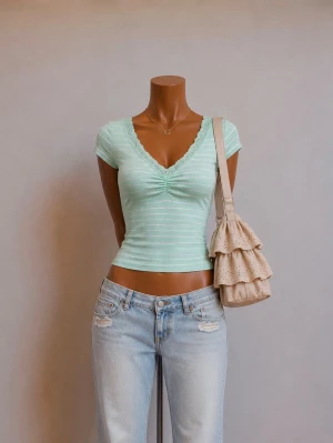 Ljusgrön ribbad v-ringad topp - Snygg ljusgrön ribbad topp med v-ringning och spetskant. Toppen har korta ärmar och ett smickrande rynk framtill. Perfekt att matcha med jeans eller kjol för en trendig look.