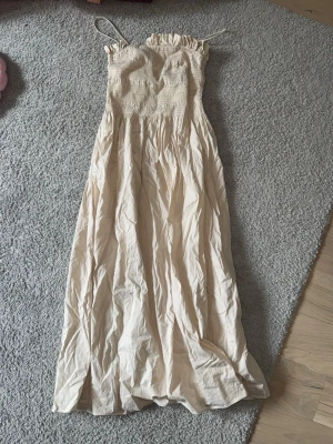 Beige långklänning med smock - Långklänning i beige med smala axelband och smockad överdel. 