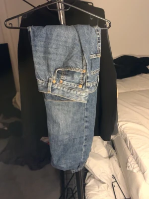 Mörk Blåa raka jeans i klassisk modell - Ett par blå jeans i klassisk rak modell med fem fickor och normal midja. Jeansen har en tidlös tvätt och detaljer i kopparfärgad metall. Perfekta för en avslappnad och stilren look. Materialet är denim i bomull.