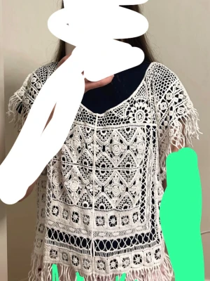 Vit virkad strandponcho med fransar - Säljer en superfin vit strandponcho i virkad spets med bohemiska mönster och fransar längs kanterna. Perfekt att slänga över bikinin på stranden. Luftig och lätt, passar perfekt till sommaren. St: S/M. Helt ny aldrig använd