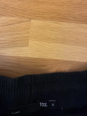 Svarta ribbade shorts från 157 - Svarta shorts från 157 med ribbad struktur och snörning i midjan. De har en avslappnad passform och är perfekta för sommarens alla dagar. Tillverkade i mjukt material för extra komfort.