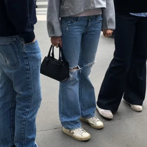 Blå bootcut jeans med slitningar - Säljer ett par ljusblå bootcut jeans med slitna detaljer och hål vid knäna. Jag är ca 160. Och dessa jeans var för stora för mig.