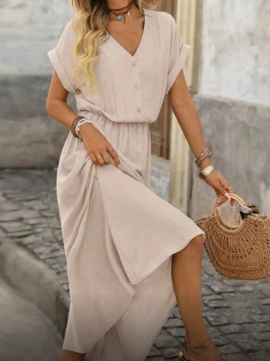 HELT NY OANVÄND Beige lång klänning med v-ringning, Medium  - HELT NY OCH OANVÄND Luftig och sval beige långklänning i viskos med v-ringad hals, knappar framtill och korta ärmar. Klänningen har ett elastiskt midjeband och kan stylas med bälte för extra form. Perfekt för varma dagar och ger en avslappnad men chic look. Storlek: Medium/38. Mått: Byst 96 cm, midja 68-102 cm, längd 139 cm, ärmlängd 24,8 cm, omkrets ärm 45.4 cm. Material: 85% viskos, 15% polyamid.