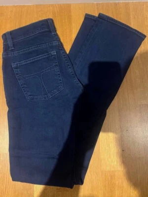 Mörkblå tiger of sweden jeans - Snygga mörkblå jeans med  passform och klassiska fickor bak. Jeansen har en enkel design utan synliga märkesloggor och är tillverkade i ett mjukt denimtyg som ger en skön känsla. Perfekta för dig som gillar en tidlös och clean stil.