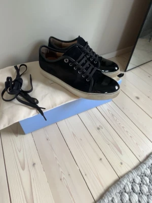 Svarta lackade sneakers från lanvin - Säljer ett par riktigt snygga lanvin i ett riktigt bra skick, jag köpte skorna för ungefär 7 månader sedan på care of carl och har använt dom sparsamt, man får med extra snören, sko påse, sko lådan, kort från Care of Car och ett cleaning kit till skorna! Vid frågor så är de bara att höra av er,(pris kan diskuteras vid snabb affär) 