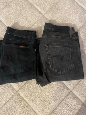 Ett par svarta jeans från nudie - Säljer två par svarta jeans från Ralph Lauren. Ena paret är mörkare svart med diskret logga på bakfickan, det andra paret är något ljusare svart med klassisk femficksdesign. Båda har raka ben och normal midja. Perfekta till en avslappnad stil.