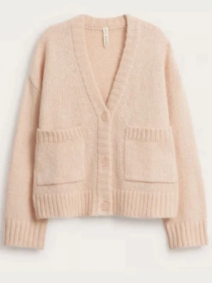 Beige oversized kofta med fickor - Mysig oversized kofta i beige med djup V-ringning och stora ribbstickade fickor framtill. Koftan har tre knappar, breda muddar och är stickad i ett mjukt material som ger en avslappnad look. Perfekt att slänga över en t-shirt eller topp. Storlek M-L men passar även mig med S !! Nypris 700 kr