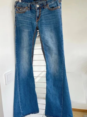 Blå bootcut jeans från True Religion - Säljer ett par blå bootcut jeans från True Religion med kontrastsömmar och slitningar framtill 🥂❣️Nypri 1600kr