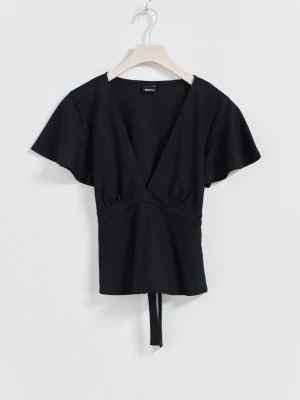 Svart omlottopp med knytband - Svart omlottopp från Gina i mjuk bomull med v-ringning och korta, lite fladdriga ärmar. Toppen har knytband i midjan som ger en snygg passform och en enkel, stilren look. Perfekt att styla med jeans eller kjol för en trendig vibe.