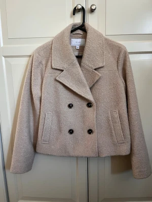 Beige teddyjacka från Vila - Säljer en beige teddyjacka från Vila med dubbelknäppning och bred krage. Jackan har två fickor framtill och är tillverkad i ett mjukt, fluffigt material som ger en trendig look. Perfekt för dig som vill ha en stilren och mysig jacka.