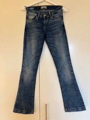 Blå bootcut jeans från LTB storlek 24X30 - Säljer ett par grymt snygga blå jeans från LTB Blue Addicted med bootcut passform och låg midja. Jeansen har fem fickor, kontrastsömmar och en cool tvättad look. Storlek 24x30. Behöver lagas vid en av hällorna bak!