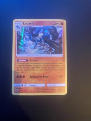 Pokémonkort Lucario Submarine Blow - Säljer ett Pokémonkort med Lucario, Submarine Blow attack och 120 HP. Kortet har en färgstark illustration med Lucario i action och text på engelska. Baksidan har klassiskt blått Pokémon-motiv med pokéboll. Perfekt för samlare eller Pokémonfans.