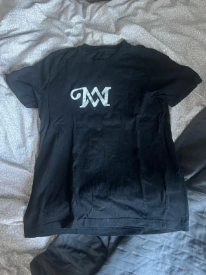 Svart M&M t-shirt - Säljer en svart M&M t-shirt med vit text, använd få gånger. Perfekt för dig som gillar Marcus och Martinus, perfekt att ha till ett par jeans eller kjol, och såklart på konserter💓💓