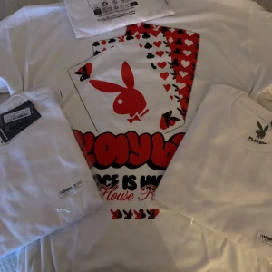 Vit Playboy t-shirt med spelkort - Säljer en vit t-shirt från Playboy med stort tryck av spelkort och den klassiska kaninloggan i rött och svart på bröstet. T-shirten har rund hals och korta ärmar. Perfekt för dig som gillar streetwear och vill sticka ut lite extra.