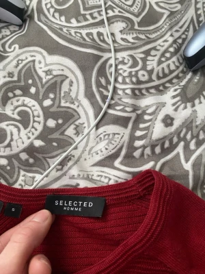 Röd långärmad tröja Selected Homme - Snygg röd långärmad tröja från Selected Homme. Tröjan har diskreta horisontella ränder på framsidan och är tillverkad i ett mjukt, tunt material. Rund halsringning och enkel, stilren design som passar perfekt till jeans.