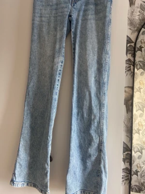 Ljusblå bootcut jeans - Säljer ett par ljusblå bootcut jeans med klassisk femficksdesign och hög midja. Jeansen har en avslappnad passform och är tillverkade i denim med lätt tvättad look. Perfekta för en trendig och avslappnad stil.